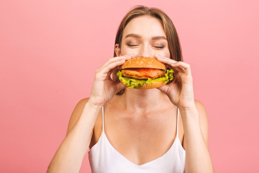 Młoda kobieta jedząca hamburgera.